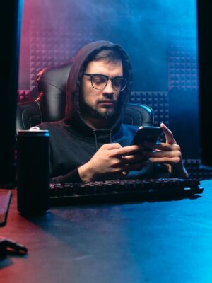 Man in dark office using smartphone, embodying cyber and tech themes.