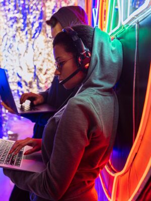 Team of cyber security experts working on laptops in a vibrant neon-lit room.